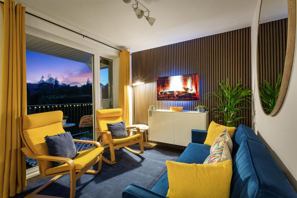 a living room with a blue couch and yellow chairs at Rigg & Rest Apartment - Bowness in Bowness-on-Windermere
