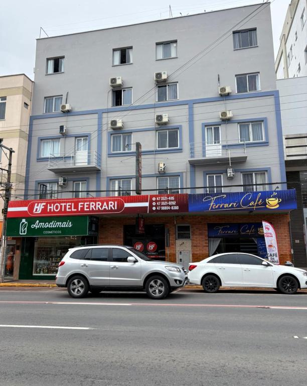 Dos coches aparcados delante de un edificio en Hotel Ferrari, en Rio do Sul