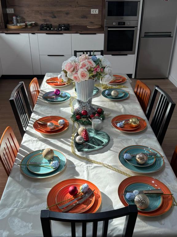 Luxury Villa Residence Corbeanca في Corbeanca: طاولة غرفة الطعام مع الأطباق والزهور عليها