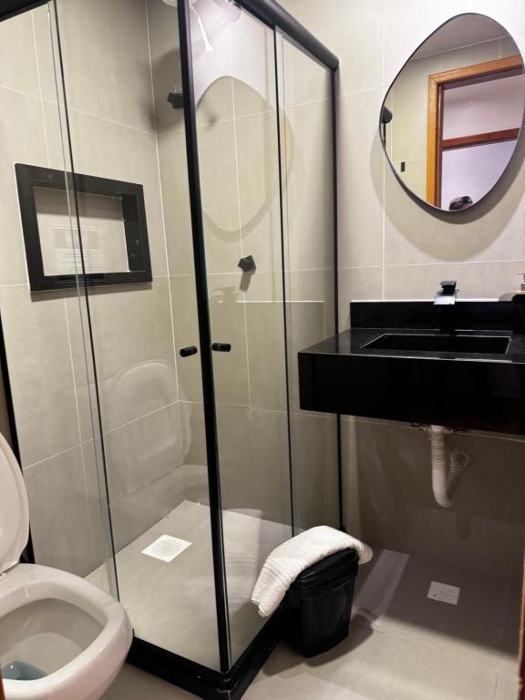 a bathroom with a shower and a toilet and a sink at Suítes Viver Arraial do Cabo in Arraial do Cabo