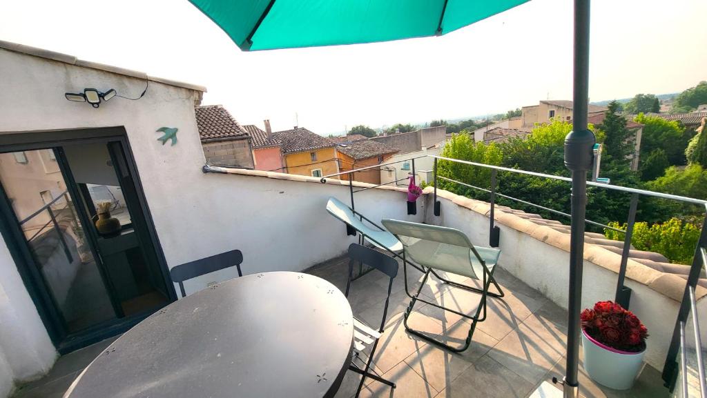 een balkon met stoelen, een tafel en een parasol bij Townhouse with rooftop in Pernes-les-Fontaines