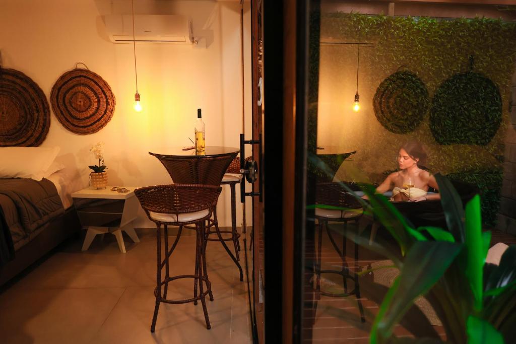 a woman sitting at a table in a room with a laptop at Pousada e Chalé Lote 22 in Ilha do Mel