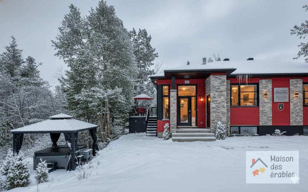 Una casa roja con un cenador en la nieve. en Mountain Spa & Pool table - Maison des Erables, en Petite-Rivière-Saint-François