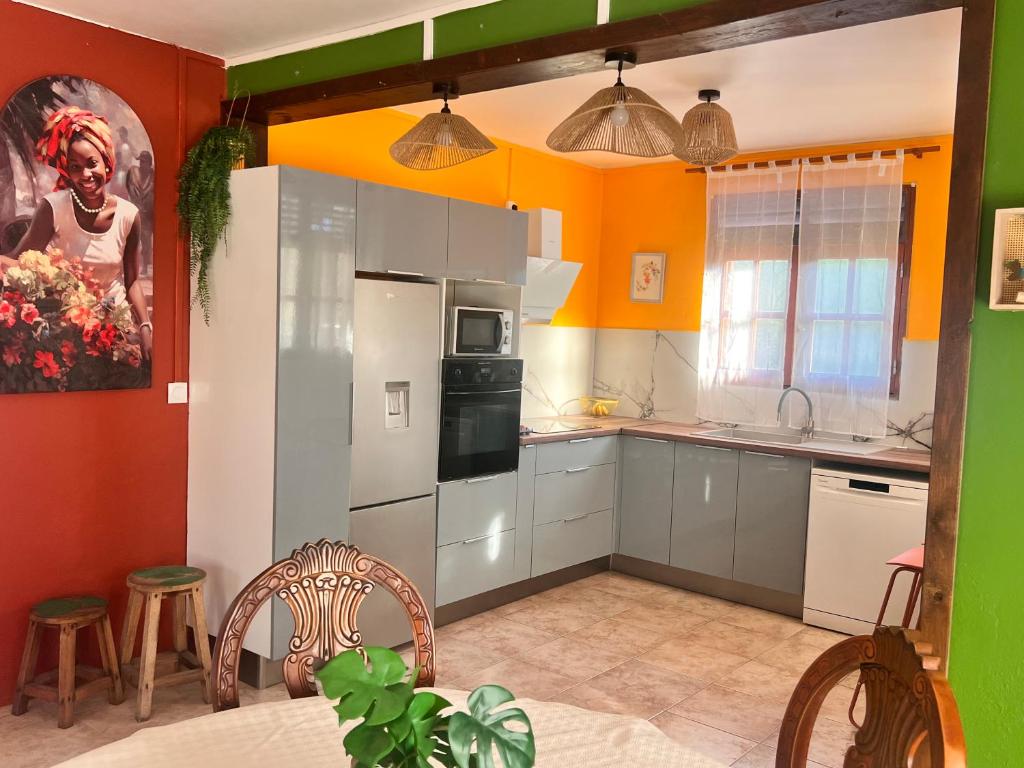 a kitchen with orange and green walls and white cabinets at Vi la dous Kreyol in Sainte-Rose