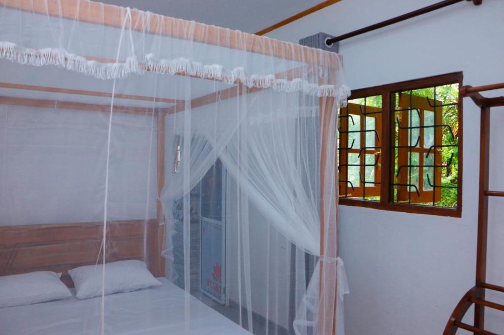 een slaapkamer met een hemelbed en een raam bij Nadi Villa Midigama in Midigama East