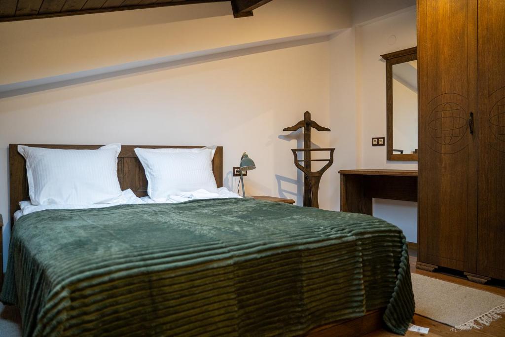 a bedroom with a bed with a green blanket and a mirror at Вила Вяра, Надежда, Любов in Neofit Rilski