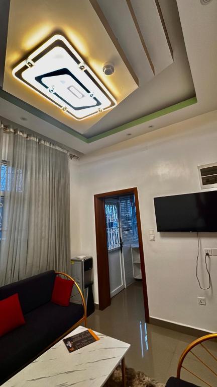 Comfort Deluxe inn في كيغالي: غرفة معيشة مع أريكة وتلفزيون على سقف