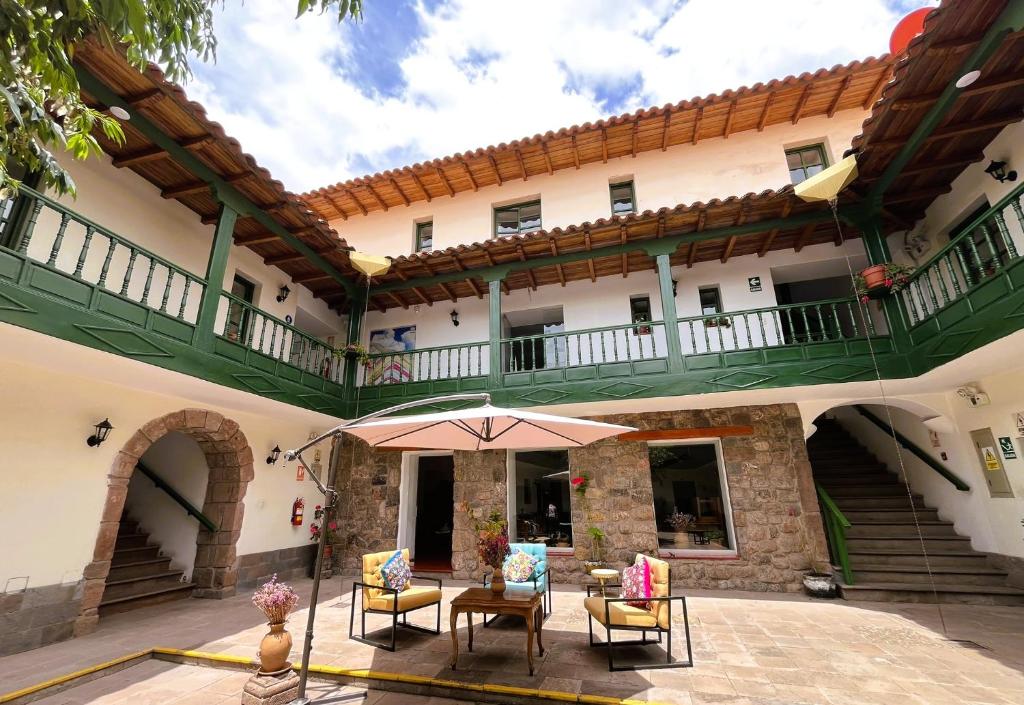 un edificio con patio con sillas y sombrilla en Usgar San Pedro Boutique, en Cusco