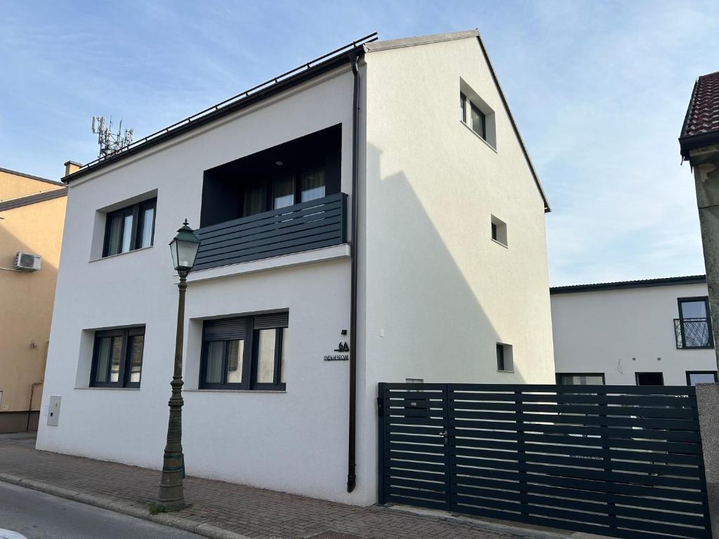 a white building with a black gate and a street light at Apartmani Bjelovar in Bjelovar