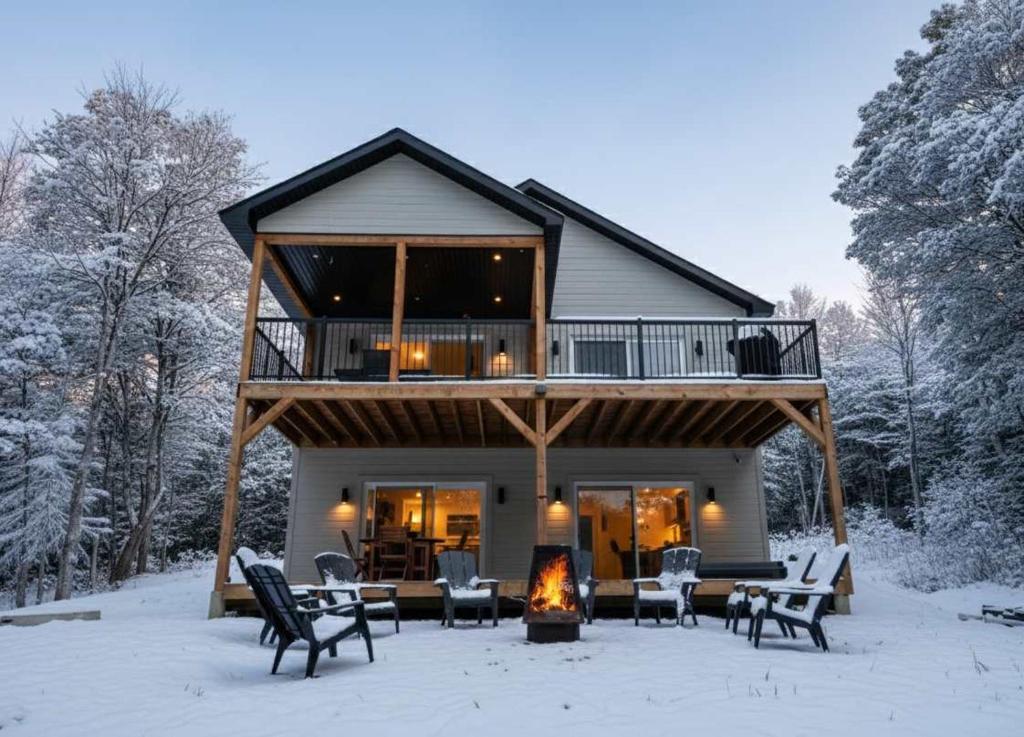 Spa and Lakefront - Oasis des chutes في Lac-Saint-Paul: كابينة خشب فيها موقد في الثلج