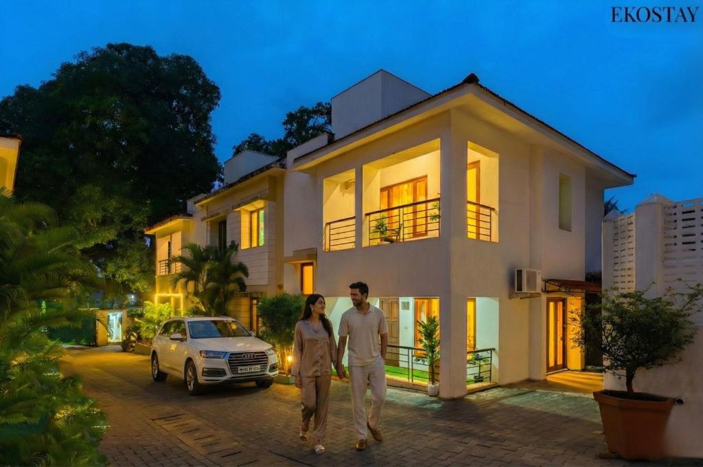 a man and woman walking in front of a house at EKO STAY - Solace Villa I Charming Villa close to Candolim Beach in Candolim