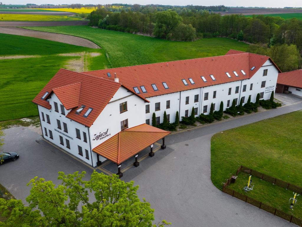 Zajazd w Biskupinie في بيسكوبين: اطلالة علوية على مبنى ابيض كبير بسقف احمر