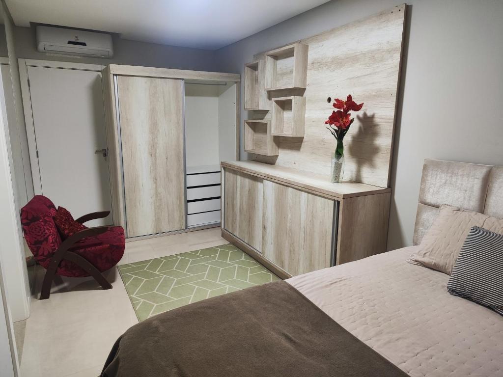 ein Schlafzimmer mit einem Bett und einer Vase aus roten Blumen in der Unterkunft Residencial Baviera in Navegantes