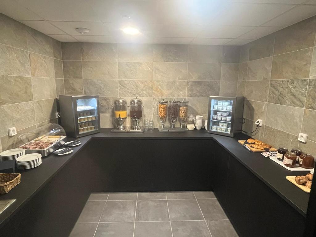 Una sala de desayunos con un mostrador con comida y bebidas. en Hotel Le Belmont, en Belmont-Tramonet