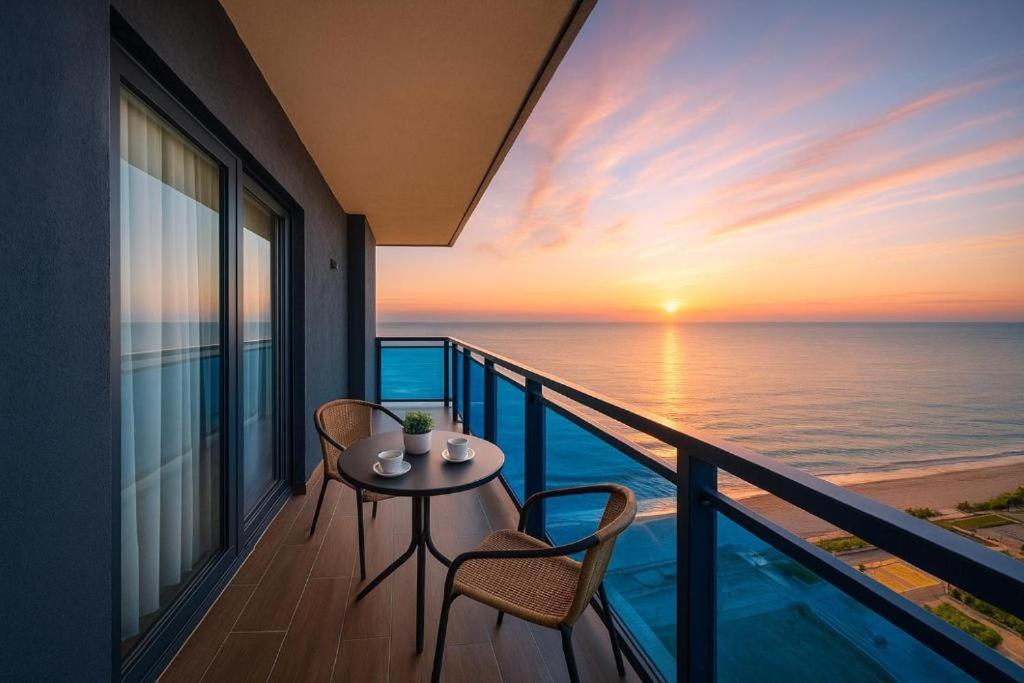 Un balcón con mesa y sillas y el mar. en Panorama Cental Hotel Batumi, en Batumi