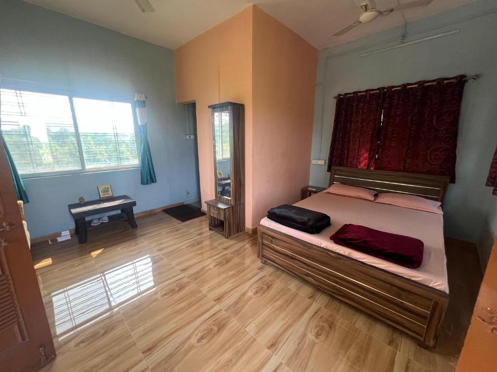 VISHWVRUND HOME STAy في Rājpīpla: غرفة نوم بسرير كبير وأرضية خشبية