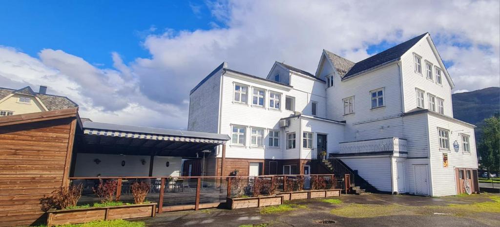 una grande casa bianca con una recinzione di fronte di Sauda Bed & Breakfast a Sauda