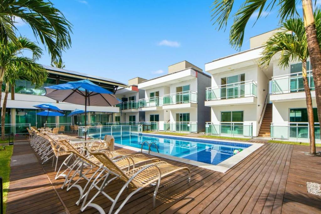 um resort com piscina, cadeiras e palmeiras em Pousada Oásis Tropical em Porto de Galinhas