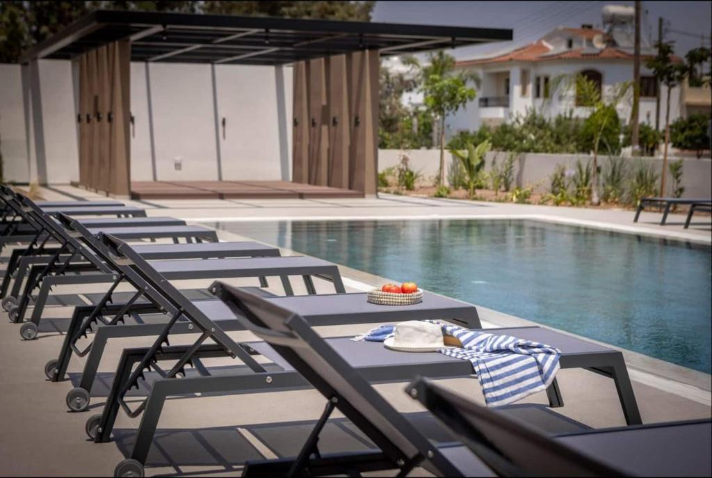 a row of lounge chairs next to a swimming pool at Kalamon Luxury Suite 105 w Pool & Gym in Livadhia
