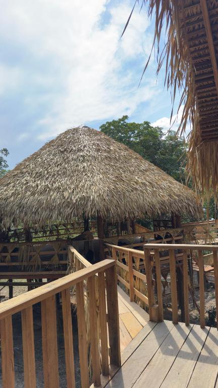 a large straw umbrella on a deck with a fence at Hotel Arara Azul in Aiparuça