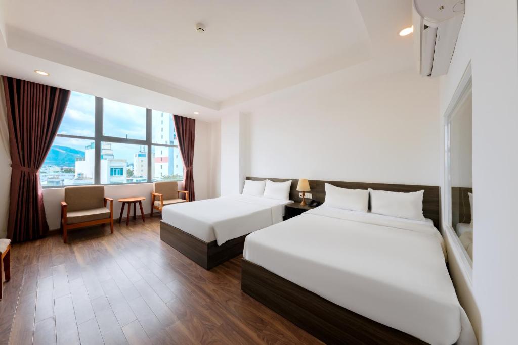 een hotelkamer met twee bedden en een tafel bij Dolphin Bay Hotel Nha Trang in Nha Trang