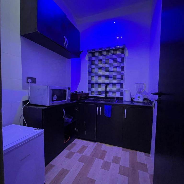 uma cozinha com luzes roxas nas paredes e uma bancada em Garnet Apartments em Iyiba