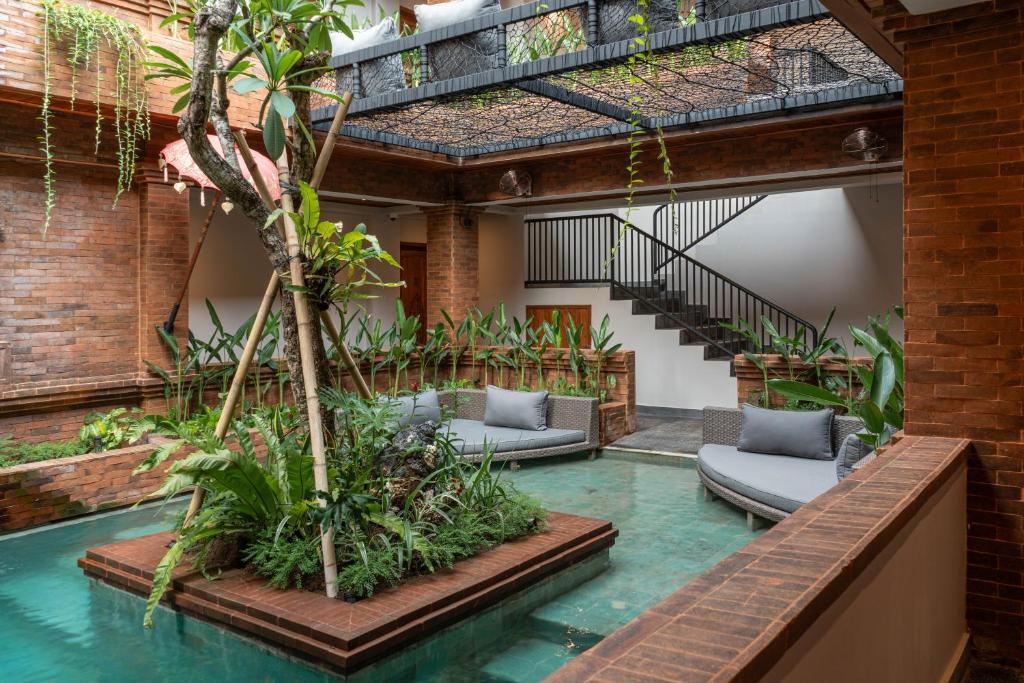 ein Hallenbad mit Stühlen und Pflanzen in einem Gebäude in der Unterkunft Baliris Home Boutique Legian in Seminyak