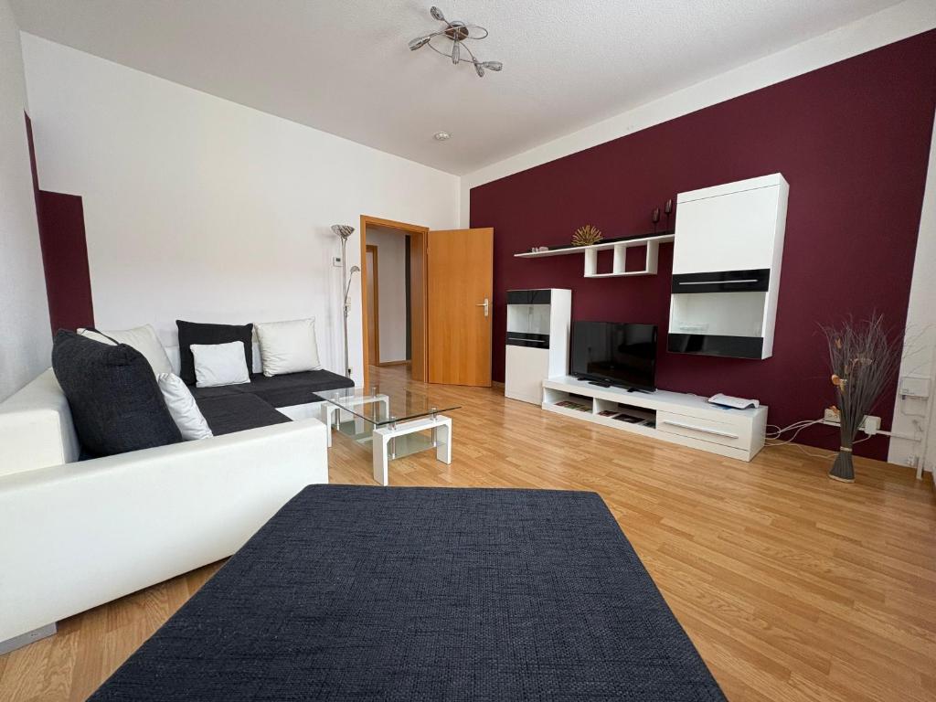 a living room with a white couch and a red wall at Gästewohnung "Kleine Auszeit" in Halberstadt