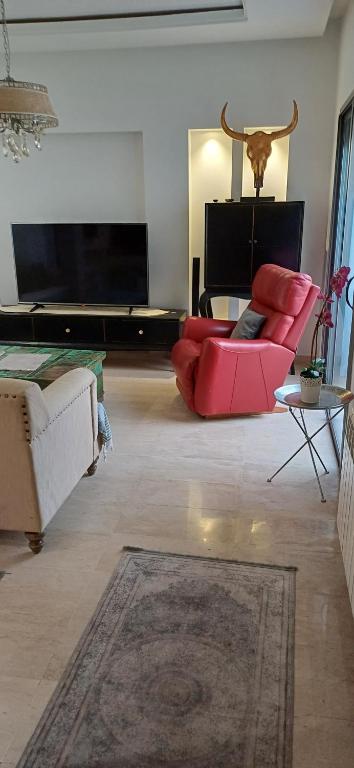 a living room with a red couch and a flat screen tv at Maison 3 in Sidi Daoud