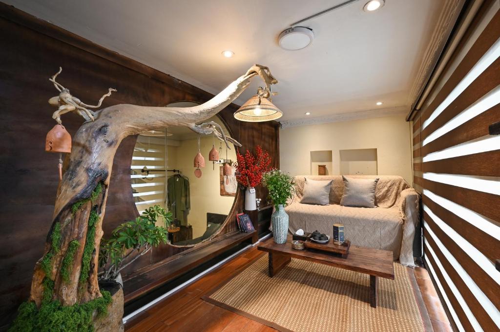 een woonkamer met een bed en een muurschildering van een boom bij RUM Studio 5 in Ho Chi Minh-stad
