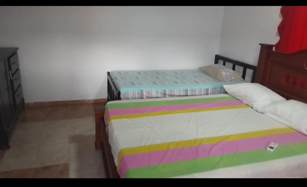 a bedroom with two twin beds with colorful sheets at Hospedaje el floral in Tolú