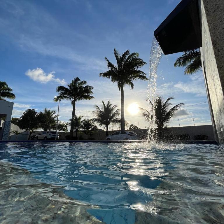 einen Brunnen in einem Pool mit Palmen in der Unterkunft Chalé das Palmeiras in Itabaiana