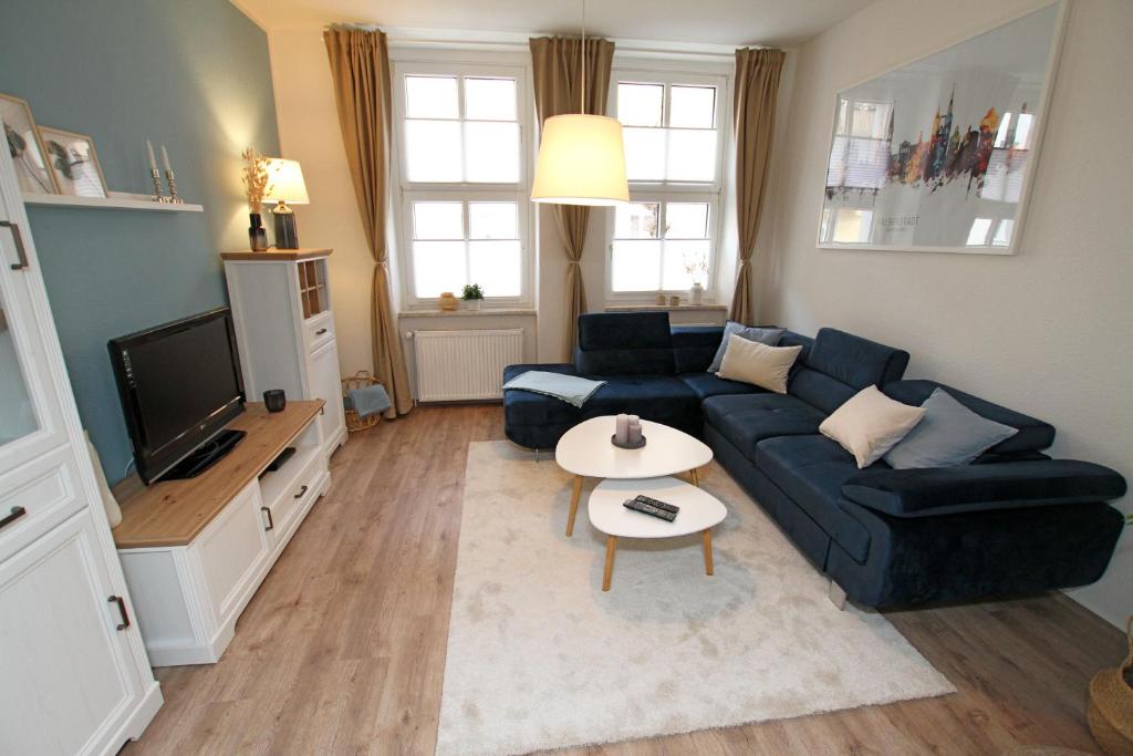 a living room with a blue couch and a tv at Gästewohnung "ZeitRaum" in Halberstadt