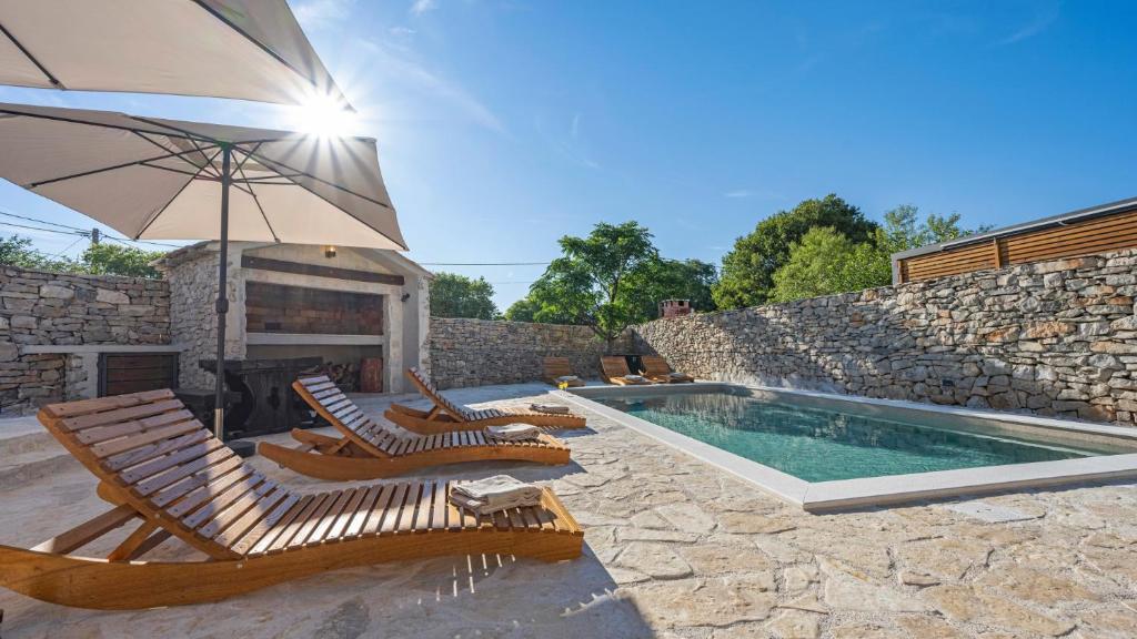 a swimming pool with lounge chairs and an umbrella at Holiday house Hedonica by Villas Guide in Mirlović Zagora