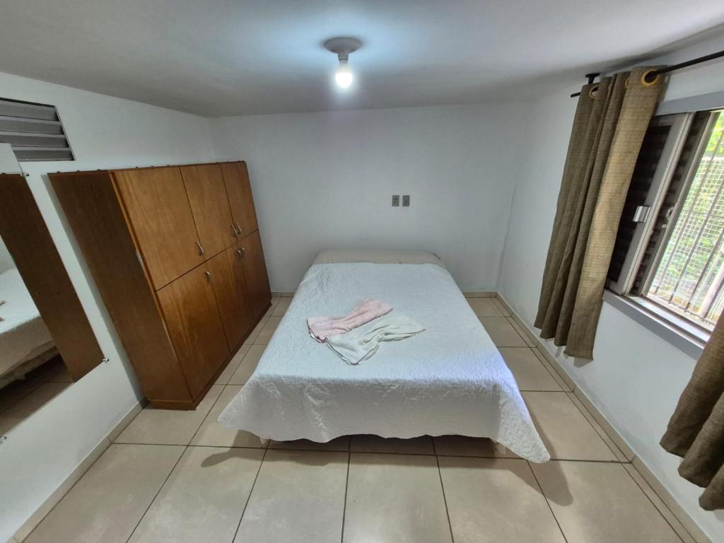 a bedroom with a bed and a wooden cabinet at Residencial Jardim Curitiba in Curitiba