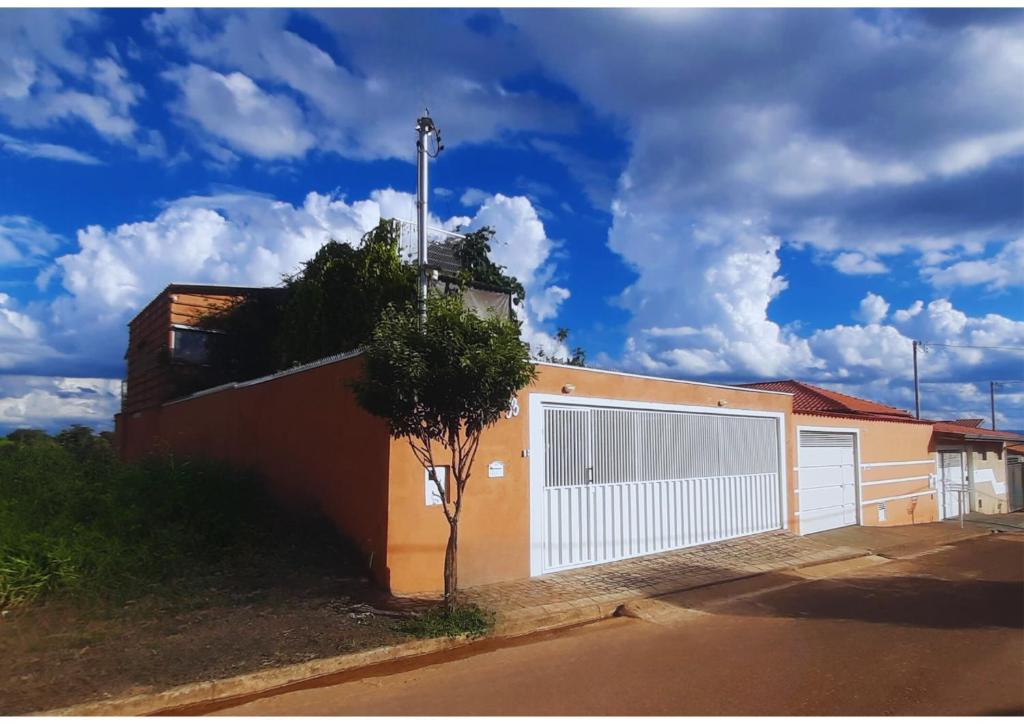 un edificio con una porta bianca e un albero di Casa Topázio no Container dos Cristais a Delfinópolis