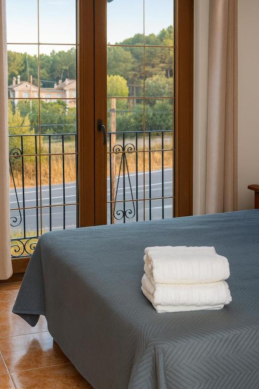a bed with three towels on it with a window at Apartamentos Turísticos San Cristóbal by Bossh! Hotels in Cuenca
