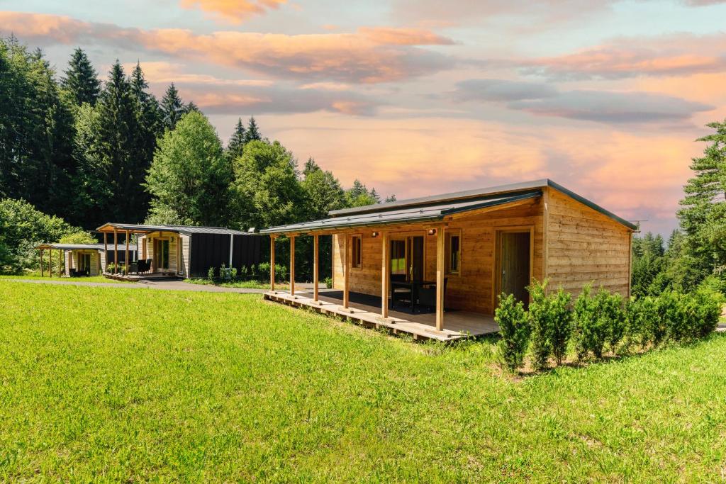 a wooden house in a field with trees at Petzen Cottages - Petzen Chalets in Feistritz ob Bleiburg