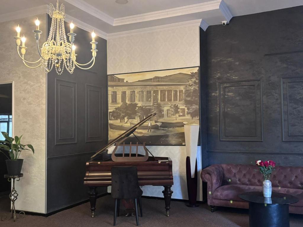 a living room with a piano and a chandelier at Aura Boutique Hotel in Batumi