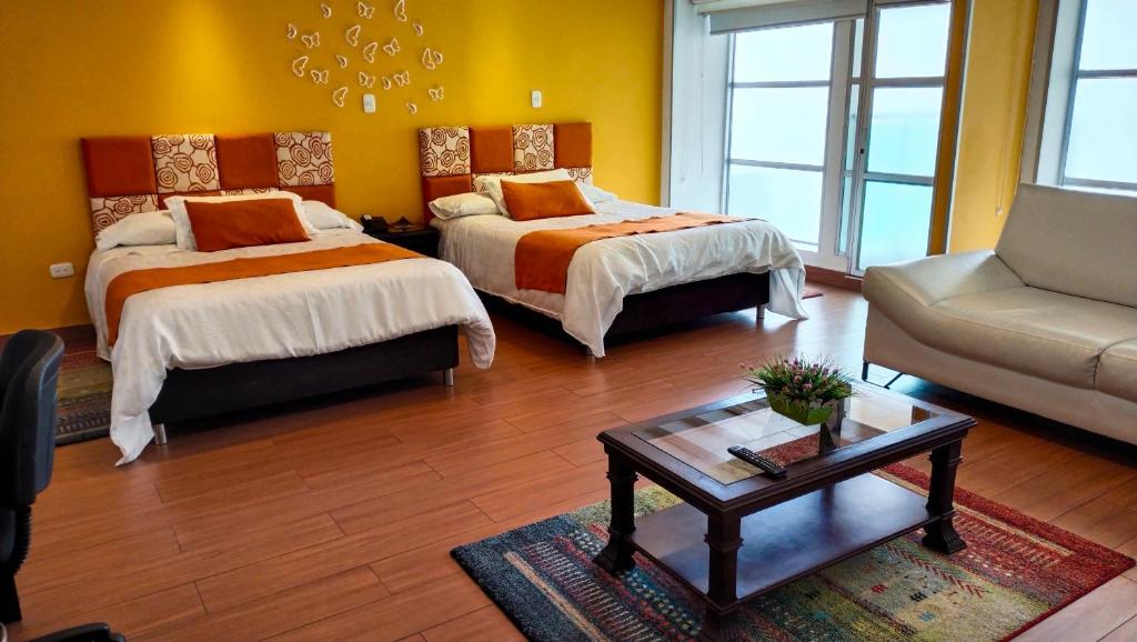 パストにあるHotel Casa Madrigalのベッド2台とソファ1台とテーブル1台がある部屋