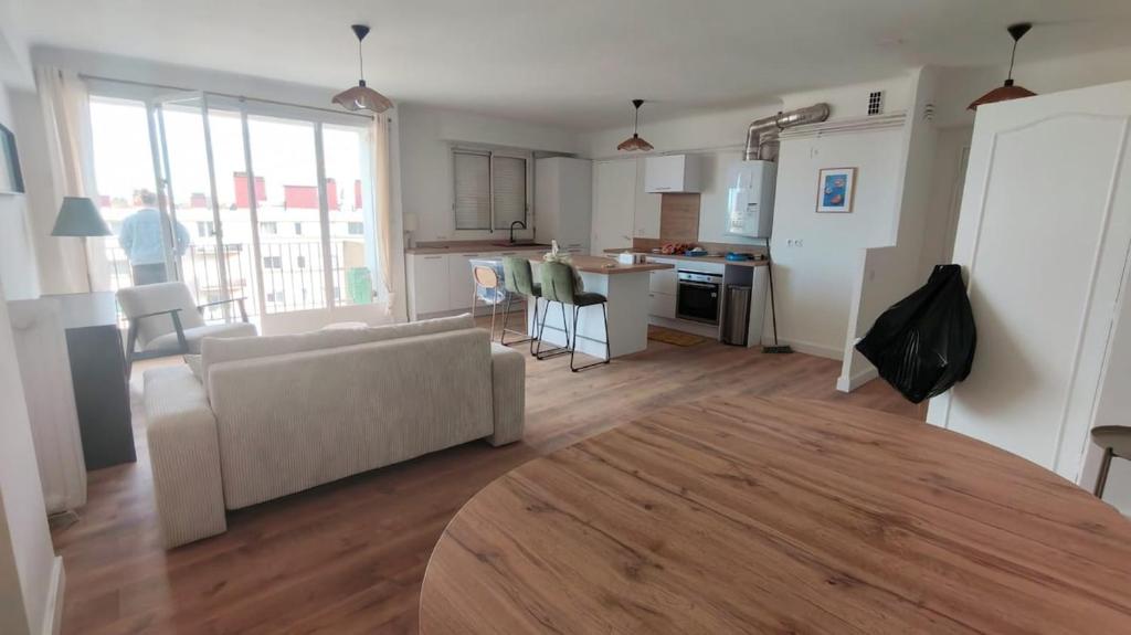 Cosy Mélodie - T3 - Parc Expo - Balcon & Parking collectif gratuit في بو: غرفة معيشة مع أريكة بيضاء ومطبخ