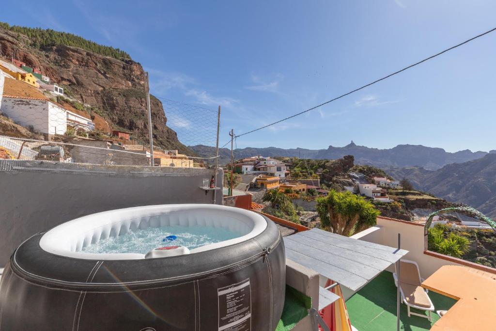 a hot tub on a balcony with a view of a city at Casa Lea Artenara in Artenara