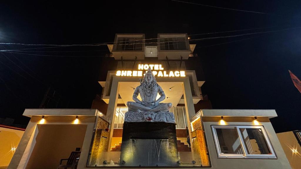 een groot standbeeld voor een gebouw 's nachts bij Travinities Hotel Shree Ji Palace in Ujjain