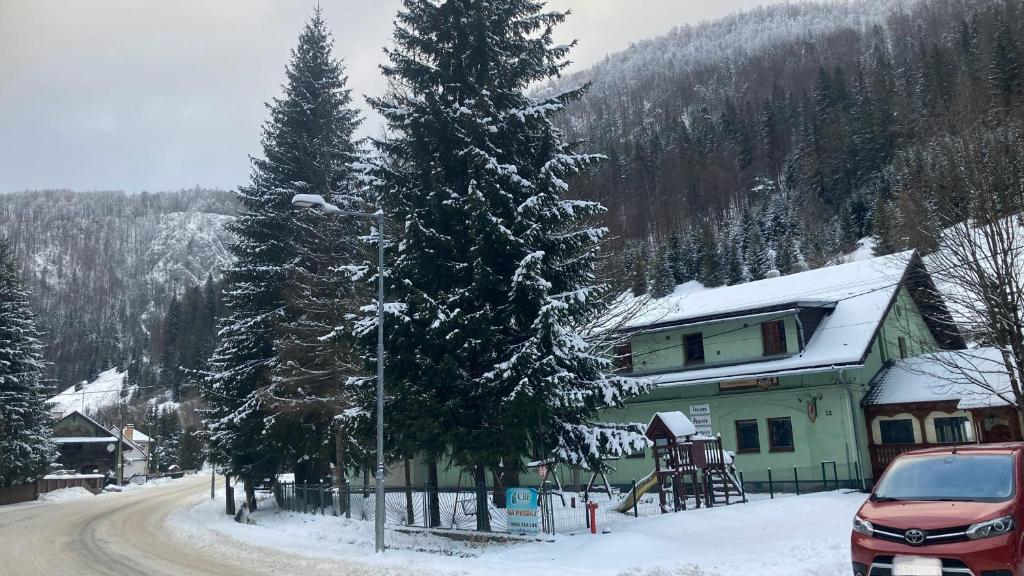 ストラチナにあるPenzión Borovica Stratenáの道路沿いに雪に覆われた木がある家