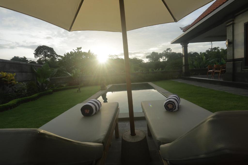 einen Tisch mit einem Sonnenschirm neben einem Pool in der Unterkunft Villa Diva in Ketewel