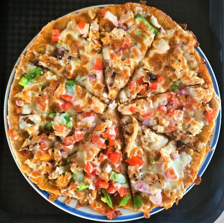 Chicken-Line Restaurant And Take Away في Mponda: بيتزا جالسة على صحن على طاولة