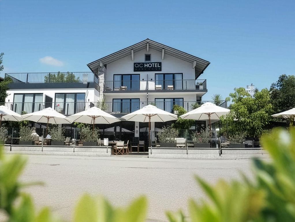 a building with tables and umbrellas in front of it at QC Quartier Chiemsee Hotel in Seebruck