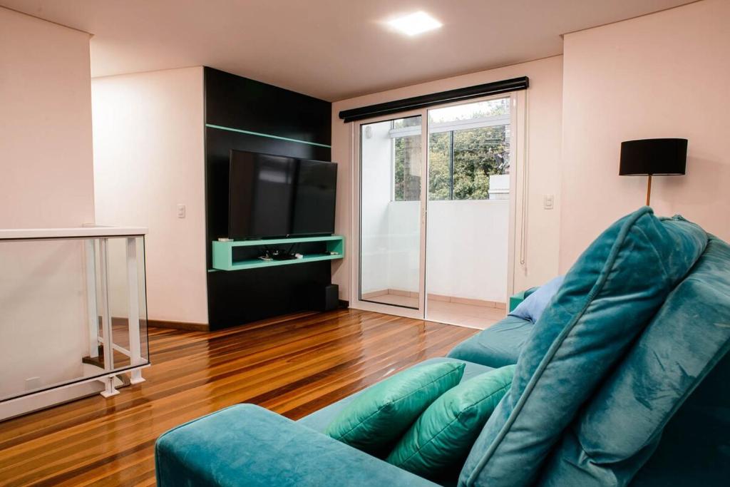 un soggiorno con un divano blu e una televisione di Casa ampla e confortável a Lajeado
