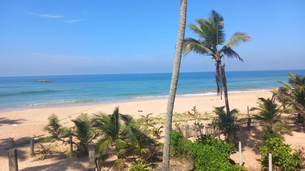 Una vista de una playa con palmeras y el océano en Pelpatha, en Balapitiya