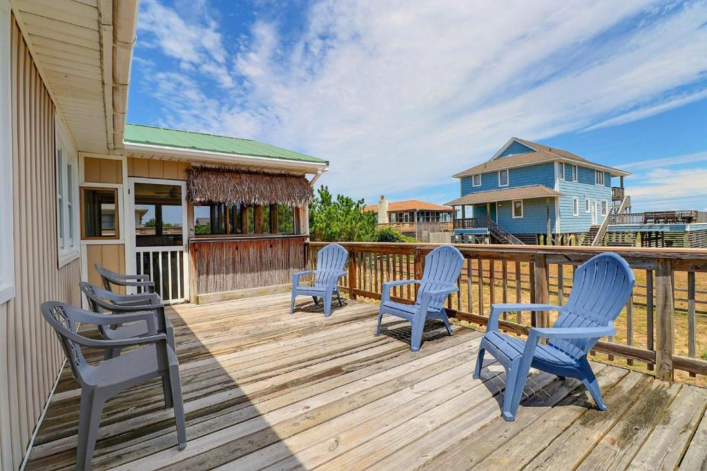 a deck with three blue chairs and a house at 4140 - Beach Carousel in Kitty Hawk